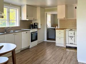cocina con electrodomésticos blancos y suelo de madera en 8 person holiday home in Varg n, en Västra Tunhem