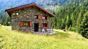 una pequeña casa de piedra en una colina en las montañas en Chalet Monin - Chalets pour 6 Personnes 671, en Modane