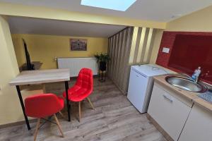a kitchen with a sink and a table and two red chairs at Apartament ultra central! in Iaşi +11 photos