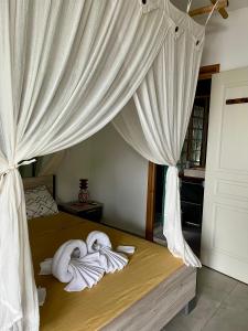 1 dormitorio con toallas en una cama con cortinas en Magnifique vue mer sur baie de Malendure en Bouillante