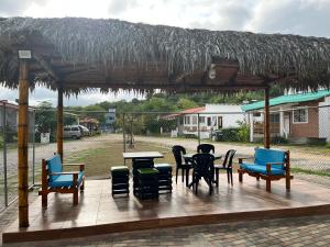 un patio con sillas, mesas y techo de paja en Cabaña Cangrejito Olon en Olón