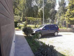 una macchina blu parcheggiata nel vialetto di una casa di Cabañas lo de Ani Casa 1 a San Carlos de Bariloche