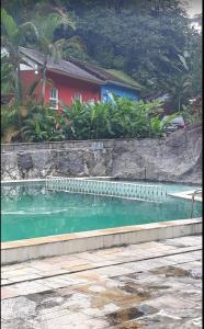 uma piscina com água verde em frente a uma casa em Pousada Estação Boca do Mato em Cachoeiras de Macacu