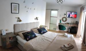 a bedroom with a white bed and a green chair at Riviera Rooms and Apartments in Rab