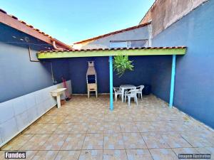 a patio with a table and chairs and a blue wall at CASA DE VERANEIO PERUIBE in Peruíbe