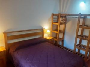 1 dormitorio con 1 cama con colcha púrpura en Cabañas lo de Ani Casa 1 en San Carlos de Bariloche