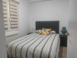 a bed with a striped comforter in a bedroom at PIso recién reformado y espacioso in Haro