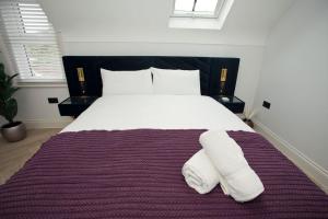 a bedroom with a large bed with two towels on it at Ultra Stylish Apt set in an affluent location in Poole +11 photos