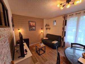 a living room with a couch and a tv at Escapade Montagne en Famille, appartement cosy avec piscine couverte in Bielle