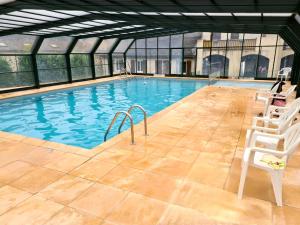 a large swimming pool with two white chairs in it at Escapade Montagne en Famille, appartement cosy avec piscine couverte in Bielle