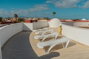eine Reihe weißer Liegestühle auf dem Dach in der Unterkunft Villa Piña in Corralejo