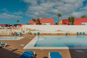 ein Swimmingpool mit Stühlen und einem Gebäude in der Unterkunft Villa Piña in Corralejo