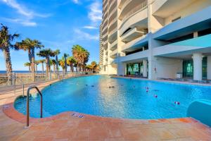 a swimming pool with palm trees and a building at Turquoise Place By Liquid Life in Orange Beach