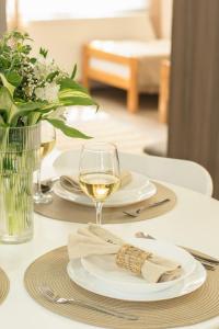 una mesa con platos y una copa de vino blanco en GoodLife Apartment en Požega