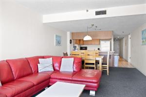310 Beach Place Condos في سانت بيتي بيتش: غرفة معيشة مع أريكة حمراء ومطبخ