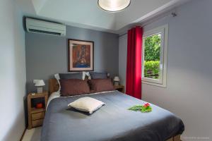 1 dormitorio con 1 cama y una ventana con cortinas rojas en Villa Eugénie en Gustavia