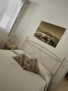 ANTICO CORTILE Favignana في فافينانا: غرفة نوم بسرير مع صورتين على الحائط