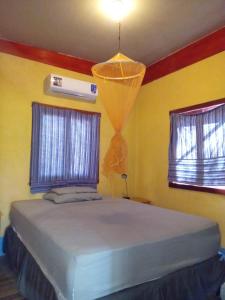 uma cama num quarto com duas janelas em Jungle Vacation Home with river and waterfall. em Santa Rita
