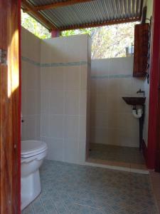 a bathroom with a toilet and a sink at Jungle Vacation Home with river and waterfall. in Santa Rita