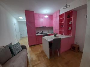 uma cozinha cor-de-rosa com um sofá e uma mesa em Apartman Talija em Kragujevac