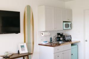 cocina con fregadero y tabla de surf en la pared en Newly Renovated! Steps from Maui's Famous Beaches!, en Wailea