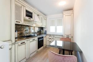 a kitchen with white cabinets and a table and chairs at Apartment Onyx Carolyne in Bistriţa