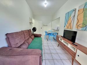 uma sala de estar com um sofá e uma televisão de ecrã plano em Apto 01 dorm c/Ar Cond, Wi-Fi (rápido), Varanda, Piscina no Guarujá