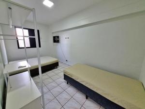 um pequeno quarto com 2 camas e uma janela em Apto 01 dorm c/Ar Cond, Wi-Fi (rápido), Varanda, Piscina no Guarujá