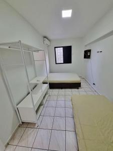 um quarto com uma cama e prateleiras em Apto 01 dorm c/Ar Cond, Wi-Fi (rápido), Varanda, Piscina no Guarujá