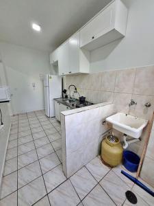 uma cozinha branca com um lavatório e um balcão em Apto 01 dorm c/Ar Cond, Wi-Fi (rápido), Varanda, Piscina no Guarujá