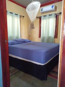 una camera da letto con letto con lenzuola e tende blu di Jungle Vacation Home with river and waterfall. a Santa Rita