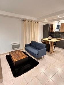 Una sala de estar con un sofá azul y una mesa. en Bel appartement, en Les Mureaux