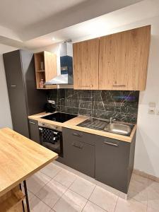 Una cocina con gabinetes de madera y un fregadero y una mesa. en Bel appartement, en Les Mureaux