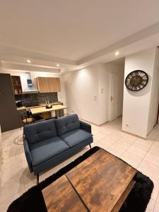 Una sala de estar con un sofá azul y un reloj. en Bel appartement, en Les Mureaux