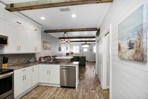 Una cocina con gabinetes blancos y electrodomésticos de acero inoxidable. en Set Sail at 5 by Pristine Properties Vacation Rentals, en Mexico Beach