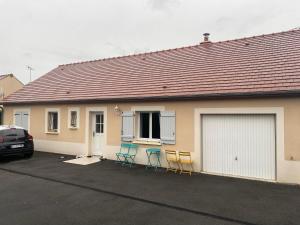 three chairs and a house with a garage at Chez Julie in Cepoy