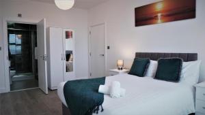 um quarto com uma grande cama branca com almofadas verdes em Sapphire House Apartments em Telford