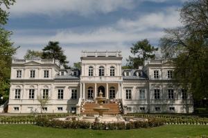 a large white mansion with a fountain in front of it at Pałac Chojnata in Wola Chojnata