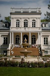 una grande casa bianca con una fontana di fronte di Pałac Chojnata a Wola Chojnata