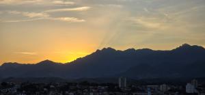 a sunset over a city with mountains in the background at Apartamento mobiliado com vista da linda Serra Mantiqueira in Cruzeiro