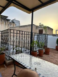 a patio with a table and potted plants on a balcony at Dar Kenz Fes in Fès