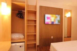 a bedroom with a closet with a tv on the wall at Ajax Hoteis in Collatina