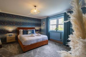a bedroom with a bed with blue walls and a window at Parc Y Deri in Aberystwyth