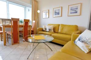 sala de estar con sofá amarillo y mesa en Strandhochhaus SG04, en Cuxhaven