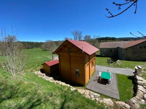 eine kleine Holzhütte mit einer Terrasse und einem grünen Stuhl in der Unterkunft Chalet de La Peyramont in Lanarce