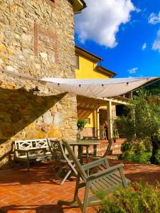une terrasse avec une table, des chaises et un parasol dans l'établissement Intero alloggio campagna Lucca, à Capannori