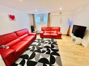 ein Wohnzimmer mit zwei roten Ledersofas und einem TV in der Unterkunft Red Rose of Summer Flat with private garden - Wilena Holiday Home in Chens-sur-Léman