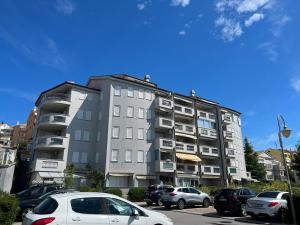 a tall building with cars parked in a parking lot at Apartman KalaMar in Crikvenica