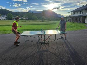 two men are standing around a ping pong table at Miglurahof in Adnet