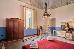 een woonkamer met een rood bed en een kroonluchter bij Palazzo Scarciglia in Minervino di Lecce